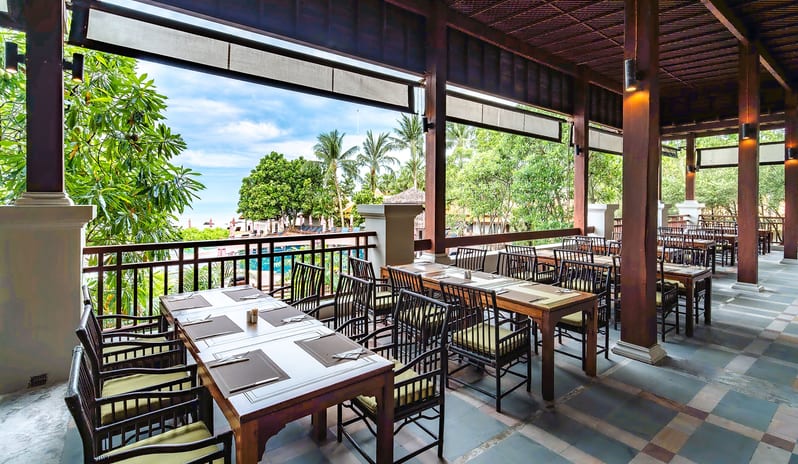 The Oriental Restaurant pen-air veranda dining area with dark wood tables, tiled flooring, and views of the resort grounds at Khaolak Laguna Resort by Kenwood Travel