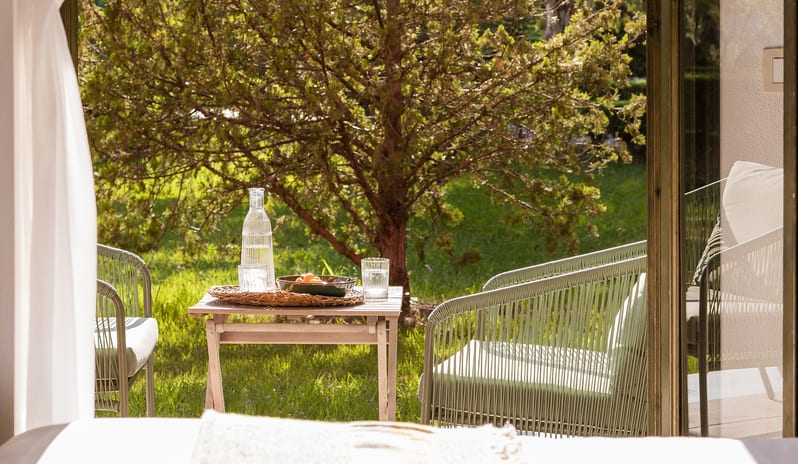 Family Interconnecting Apartment with Veranda outdoor seating and refreshments on a wooden terrace table surrounded by lush greenery at Grecotel LUXME Costa Botanica by Kenwood Travel