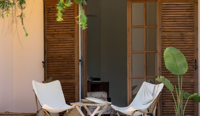 Family Interconnecting Apartment with Verandaoutdoor balcony seating area with two chairs, a patio table, potted plants, and wooden French doors at Grecotel LUXME Costa Botanica by Kenwood Travel