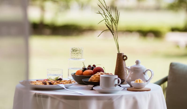 Family Interconnecting Room Shaded Veranda Gourmet breakfast served on a white-clothed table on a private shaded veranda, overlooking a lush green garden at Grecotel LUXME Costa Botanica by Kenwood Travel