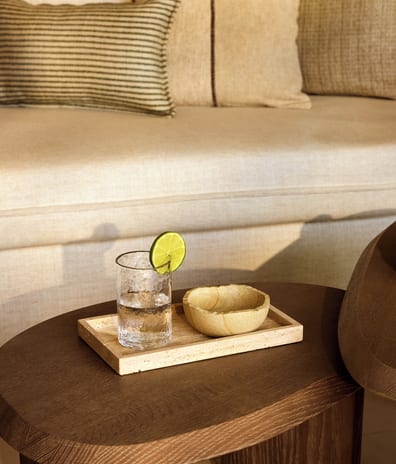 Double Room Garden View glass of iced water with a fresh lime garnish on a stone tray, showcasing a relaxing afternoon vibe in an upscale resort lounge at Sani Club by Kenwood Travel