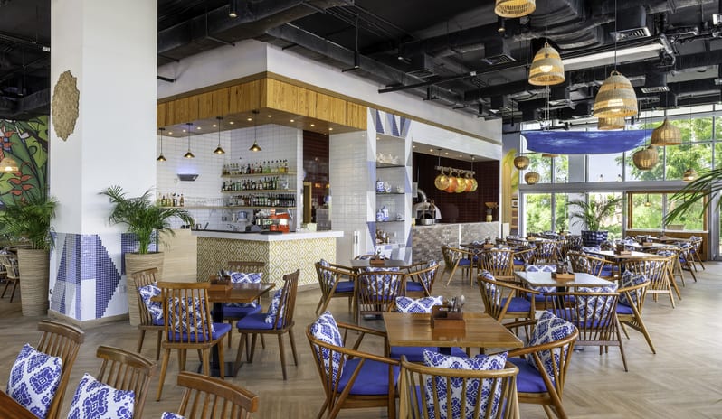 Sands mix of rustic wood elements, nautical blue cushions, industrial exposed ceilings, and tropical plants at Centara Mirage Beach Resort Dubai by Kenwood Travel