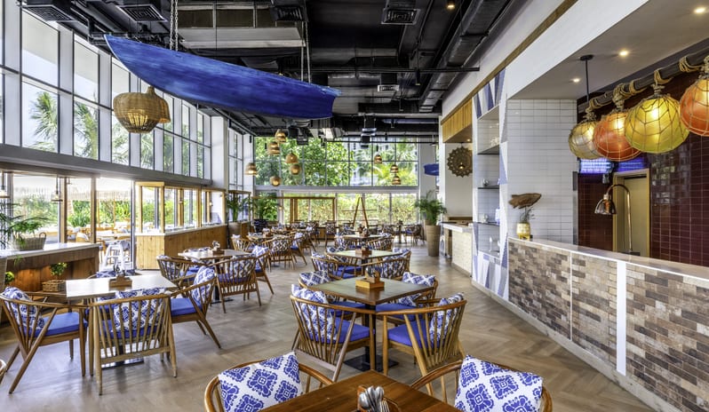 Sands mix of rustic wood elements, nautical blue cushions, industrial exposed ceilings, and tropical plants at Centara Mirage Beach Resort Dubai by Kenwood Travel