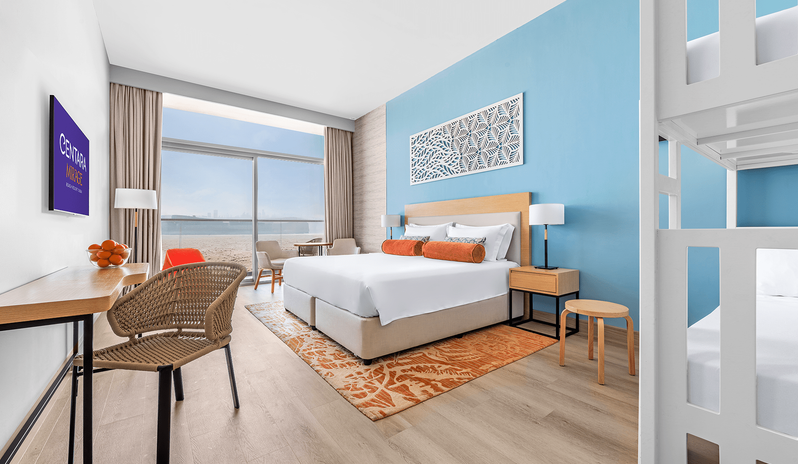 Mirage Family Room with Bunk Beds room featuring a large bed, white wooden bunk beds, and bright blue accent wall at Centara Mirage Beach Resort Dubai by Kenwood Travel