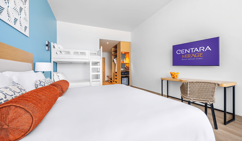 Mirage Family Room with Bunk Beds wall-mounted TV, wooden work desk, bunk beds, and a king bed with orange accent pillows at Centara Mirage Beach Resort Dubai by Kenwood Travel