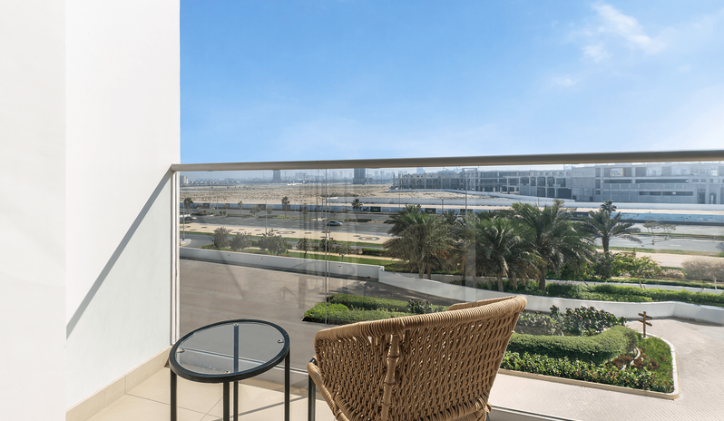 Mirage Family Room with Bunk Beds woven armchair, a small glass table, and a glass railing overlooking palm trees and the city skyline at Centara Mirage Beach Resort Dubai by Kenwood Travel
