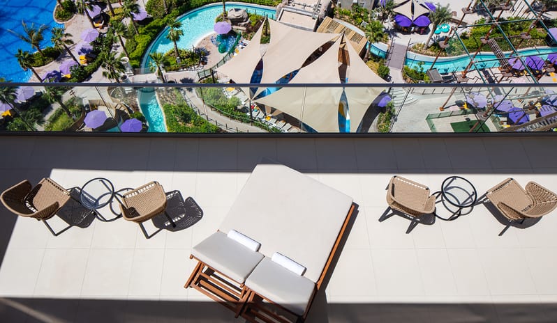Luxury resort suite terrace with sunbeds and outdoor seating looking down at a tropical waterpark and pool complex at Centara Mirage Beach Resort Dubai by Kenwood Travel