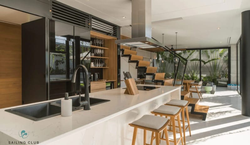 One Bedroom Pool Villa white marble island with bar stools, an open-air dining area, and sleek black cabinetry in a Polaris Villa at Sailing Club Signature Resort Phu Quoc Hotel by Kenwood Travel