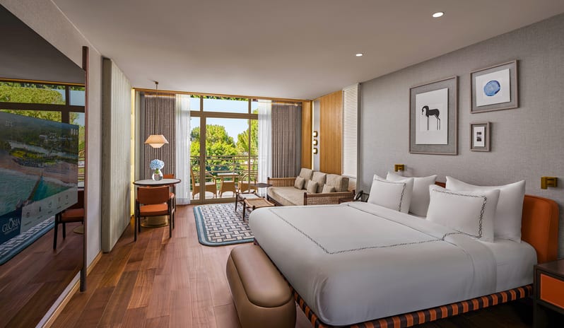 Superior Room king bed, hardwood floors, a small sitting area, and a private balcony view at Gloria Serenity Resort by Kenwood Travel