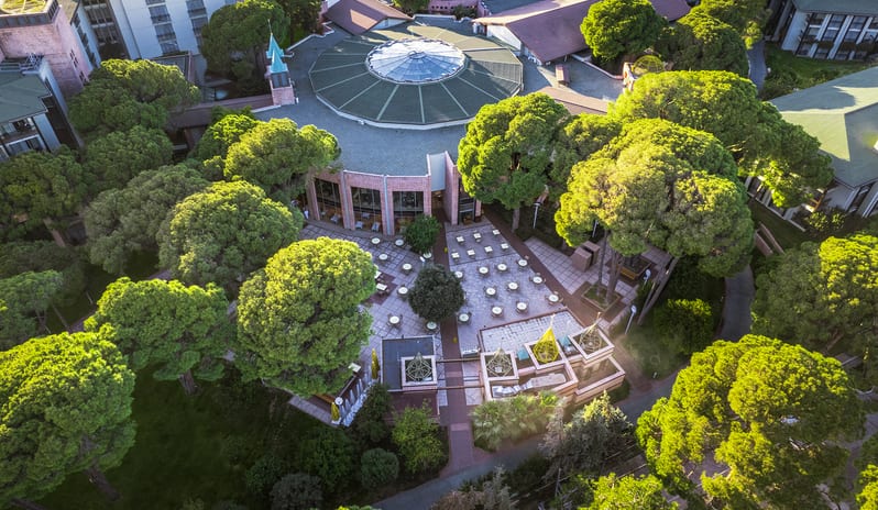 Mythos eco-friendly hotel resort integrated with dense green trees and a paved outdoor patio at Gloria Verde by Kenwood Travel
