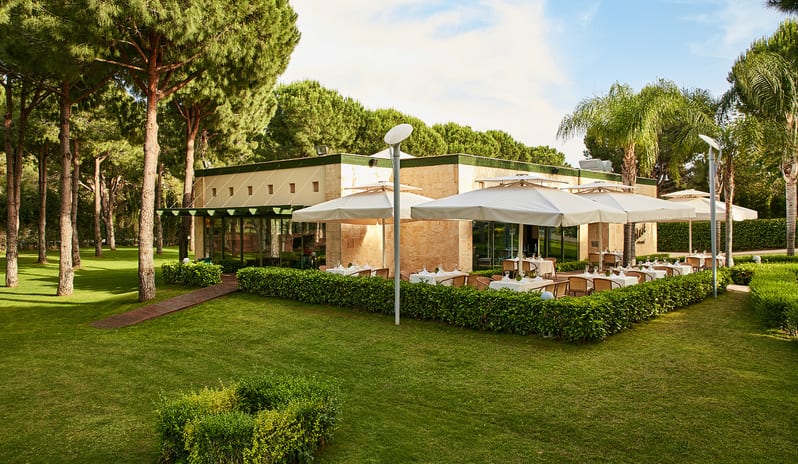 Select Restaurant garden restaurant terrace at a luxury resort nestled among tall pine trees and palm trees at Gloria Verde by Kenwood Travel