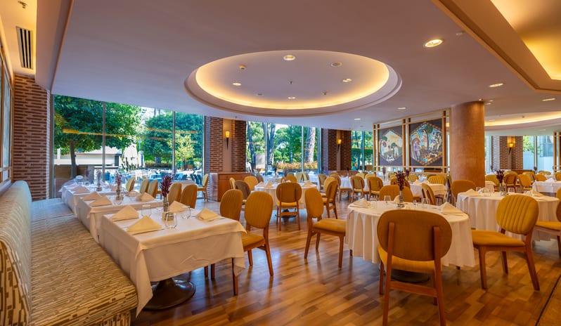 Mythos round recessed ceiling lights, wooden floors, and elegant table setups at Gloria Verde by Kenwood Travel