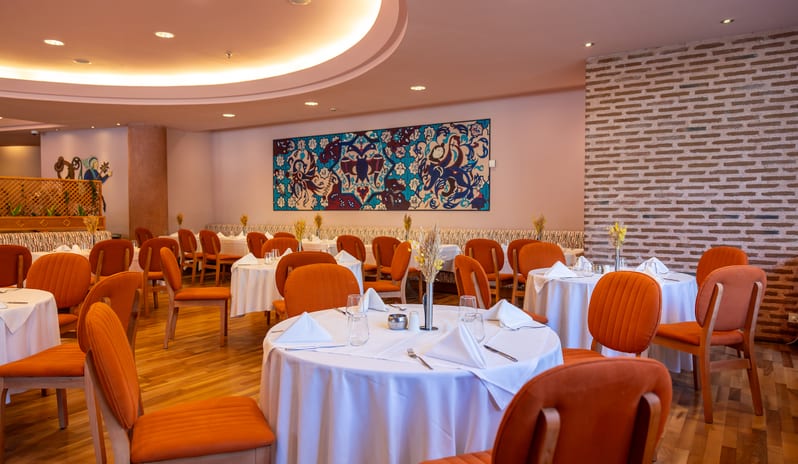 Mythos round recessed ceiling lights, wooden floors, and elegant table setups at Gloria Verde by Kenwood Travel