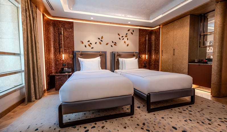 Vip Villa twin beds with white linens, built-in wooden wardrobes, a mini bar area, a patterned area rug, and floor-to-ceiling window curtains at Gloria Serenity Resort by Kenwood Travel