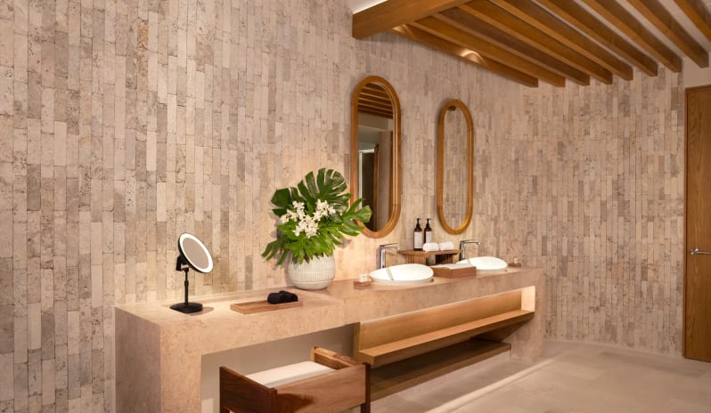 Honeymoon Suite Ocean View bathroom with dual sinks, wooden oval mirrors, and stone walls at Impression Isla Mujeres by Secrets by Kenwood Travel