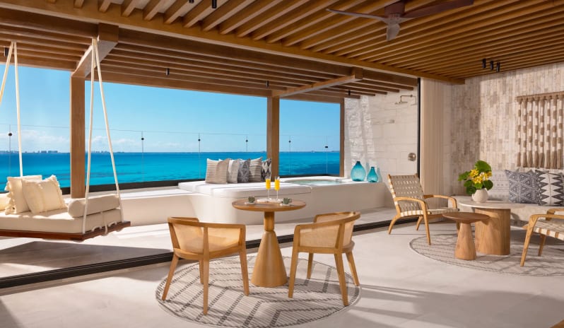 Honeymoon Suite Ocean Front living area with a patio swing, lounge seating, and panoramic ocean views at Impression Isla Mujeres by Secrets by Kenwood Travel
