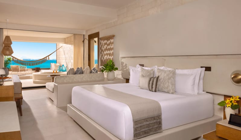 Paramount Suite Ocean Front bedroom with beachfront balcony, private jacuzzi, and hammock at Impression Isla Mujeres by Secrets by Kenwood Travel