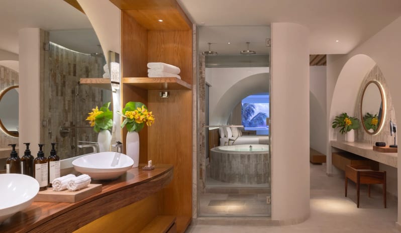 Presidential Suite master bathroom with dual vessel sinks, glass shower, and vanity desk at Impression Isla Mujeres by Secrets by Kenwood Travel