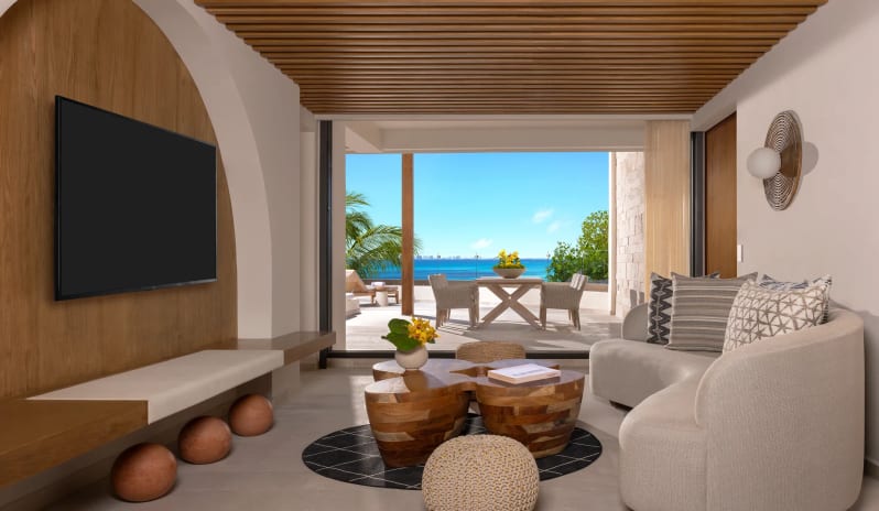 Presidential Suite king suite living room with a curved sofa, custom wood ceiling, and panoramic ocean view terrace at Impression Isla Mujeres by Secrets by Kenwood Travel