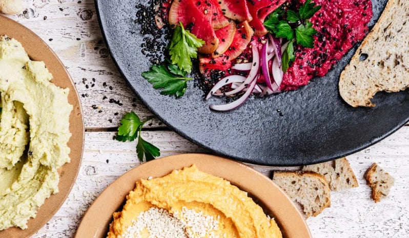 Unik the Kitchen Healthy appetizer assortment with colorful vegetable dips, hummus, and sliced bread at a restaurant at Impression Isla Mujeres by Secrets by Kenwood Travel