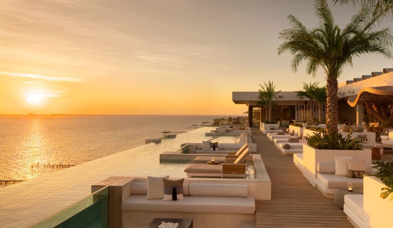 Unik the Kitchen rooftop infinity pool and oceanfront lounge area at sunset at Impression Isla Mujeres by Secrets by Kenwood Travel