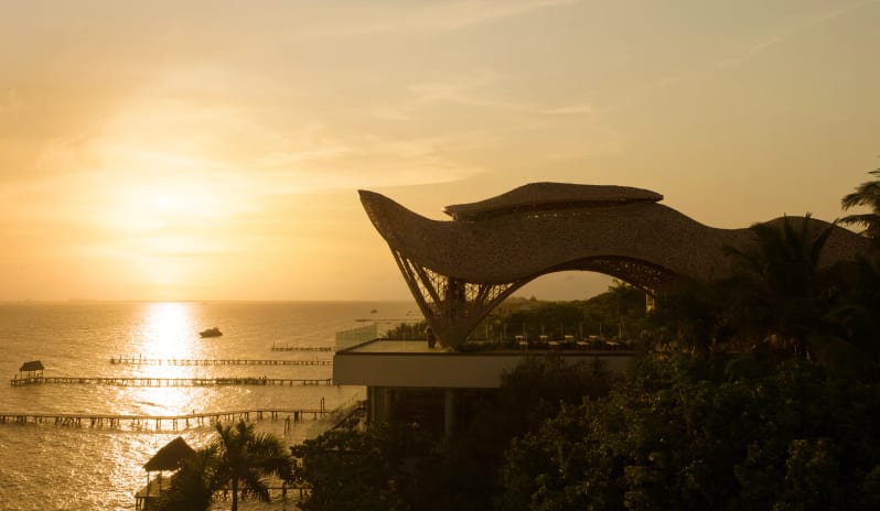 The Temple rooftop with a unique woven bamboo canopy structure overlooking the ocean at sunset at Impression Isla Mujeres by Secrets by Kenwood Travel