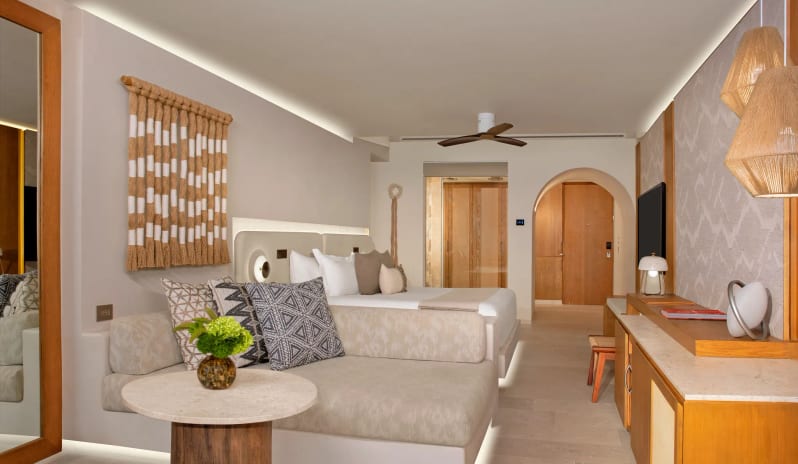 Junior Suite King king bed, modern boho decor, a comfortable lounge sofa, and warm ambient lighting at Impression Isla Mujeres by Secrets by Kenwood Travel
