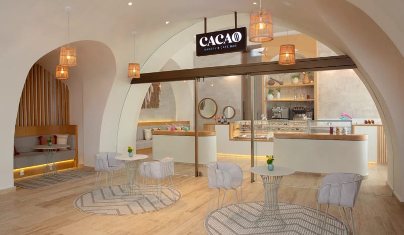 Cacao bakery and cafe bar entrance with stylish indoor seating and a pastry display counter at Impression Isla Mujeres by Secrets by Kenwood Travel