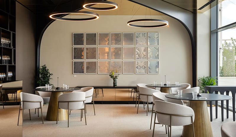Harry’s Piccolo Poreč modern circular tables, beige armchairs, and circular halo pendant light fixtures at Pical Resort, Valamar Collection by Kenwood Travel