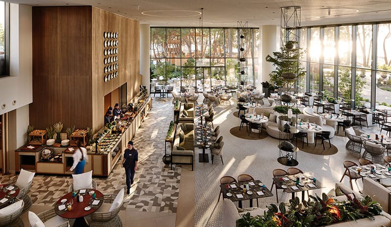 Parenzana modern, sunlit dining hall at Parenzana Restaurant featuring wooden accents, plush seating, and floor-to-ceiling glass walls at Pical Resort, Valamar Collection by Kenwood Travel