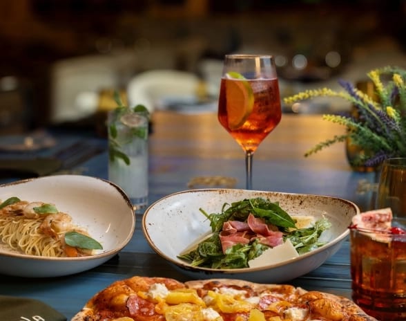 Tavola Authentic Italian pizza, pasta, salad, and cocktails set on a dining table at Moon Palace The Grand Punta Cana by Kenwood Travel
