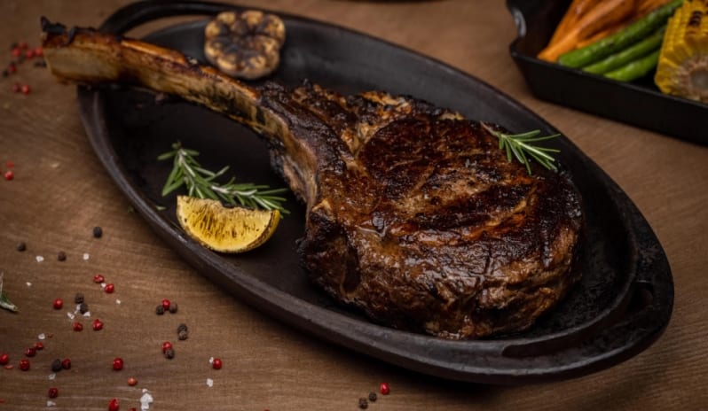 JC Steakhouse Grilled bone-in tomahawk steak on a sizzler platter at Moon Palace The Grand Punta Cana by Kenwood Travel