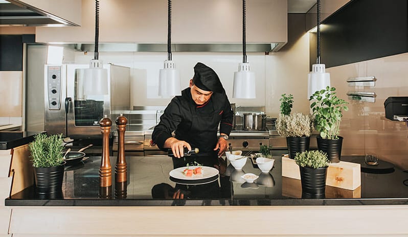 Miramare Restaurant by Fratelli Chef carefully plating a gourmet dish at the open kitchen counter at Pical Resort, Valamar Collection by Kenwood Travel