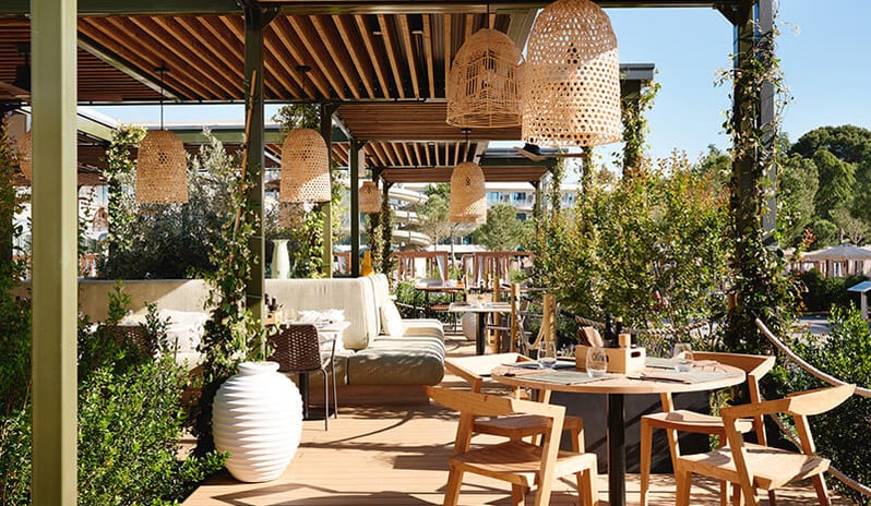Oliva Grill Outdoor dining terrace with woven lamps and green banquette seating at Pical Resort, Valamar Collection by Kenwood Travel