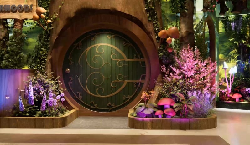 Wonderwoods Enchanted forest lounge entrance with a circular wooden door and hanging foliage at Moon Palace The Grand Punta Cana by Kenwood Travel