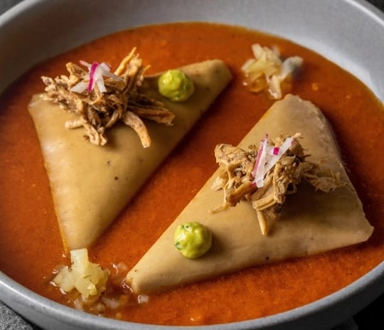 Madremía Triangular gourmet tamales with shredded chicken garnish in red salsa at Moon Palace The Grand Punta Cana by Kenwood Travel