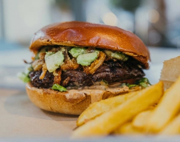 Camino Street Artisanal beef burger with avocado and crispy onions served alongside french fries at Moon Palace The Grand Punta Cana by Kenwood Travel