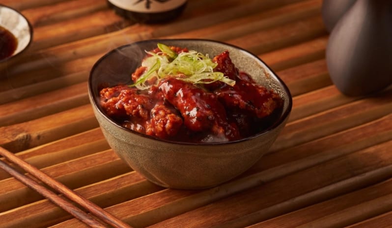 Jade Bowl of glazed spicy fried chicken garnished with green onions at Moon Palace The Grand Punta Cana by Kenwood Travel