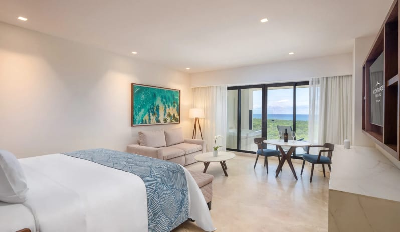 Grand Superior Deluxe Ocean View plush king bed, modern seating, and private terrace overlooking the sea at Moon Palace The Grand Punta Cana by Kenwood Travel