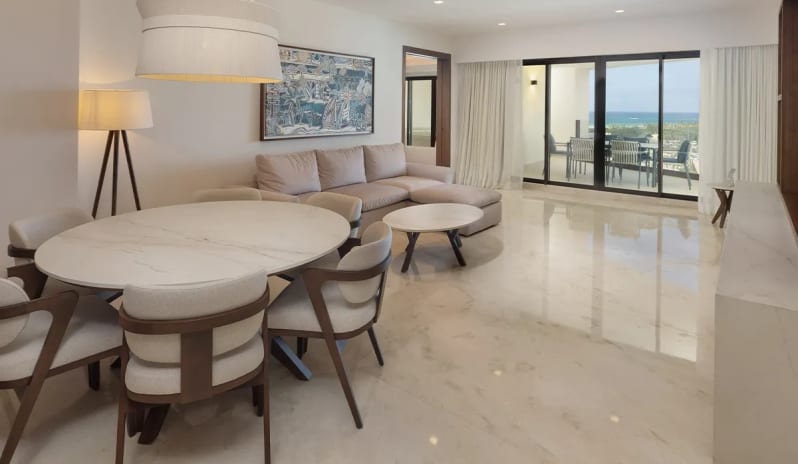 Grand Presidential Suite Ocean View living room with dining area and oceanfront balcony at Moon Palace The Grand Punta Cana by Kenwood Travel
