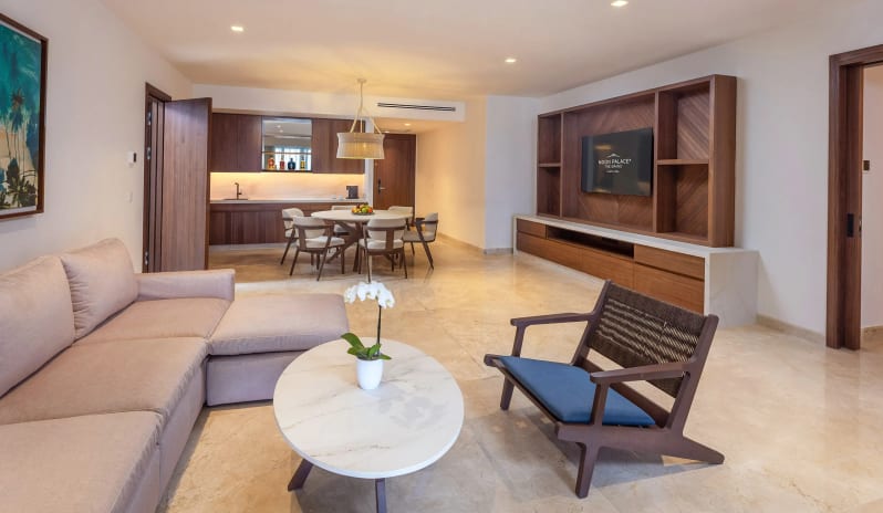 Grand Presidential Suite sectional sofa, marble coffee table, wall-mounted TV, dining table, and bar counter at Moon Palace The Grand Punta Cana by Kenwood Travel