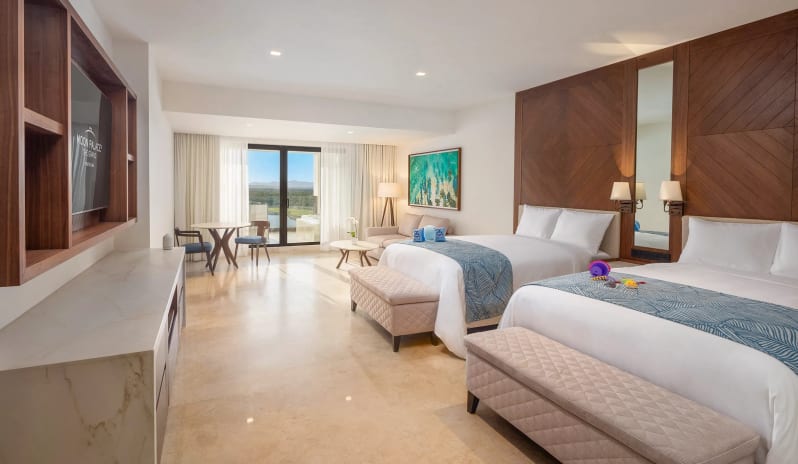 Grand Family Suite Golf View bedroom with two double beds, dark wood geometric headboards, TV console, seating area, and sliding doors leading to a golf course view balcony at Moon Palace The Grand Punta Cana by Kenwood Travel