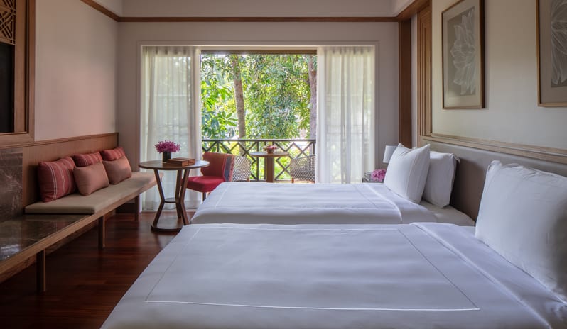 Club Two Bedroom Family Suite two double beds with crisp white linen, a daybed bench, and a balcony opening to lush tropical foliage at Anantara Hua Hin Resort  by Kenwood Travel