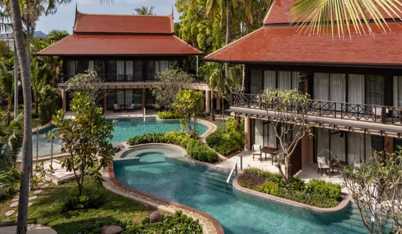 Deluxe Pool Access Elevated view of Thai-style resort villas and ground-floor Deluxe Pool Access rooms around a lagoon swimming pool at Anantara Hua Hin Resort  by Kenwood Travel