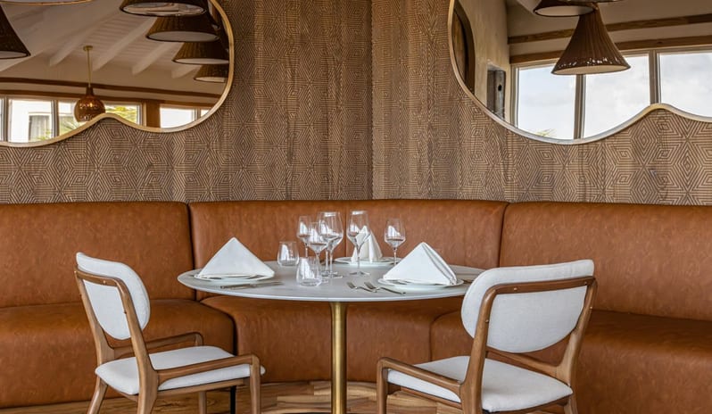 Brine restaurant dining nook with a curved brown leather booth and fine table setting at Salterra, A Luxury Collection Resort & Spa, South Caicos by Kenwood Travel