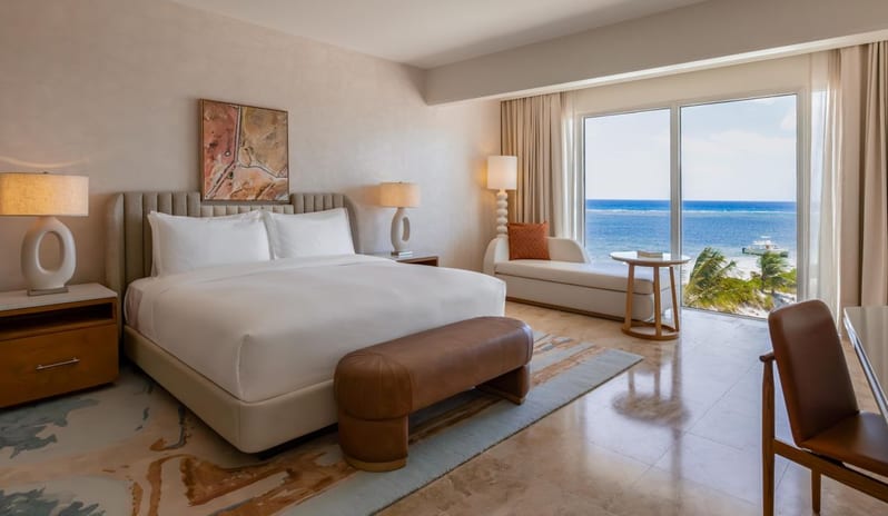 One Bedroom Ocean View King Suite Balcony king bedroom in a hotel suite with modern decor and floor-to-ceiling ocean views at Salterra, A Luxury Collection Resort & Spa, South Caicosby Kenwood Travel