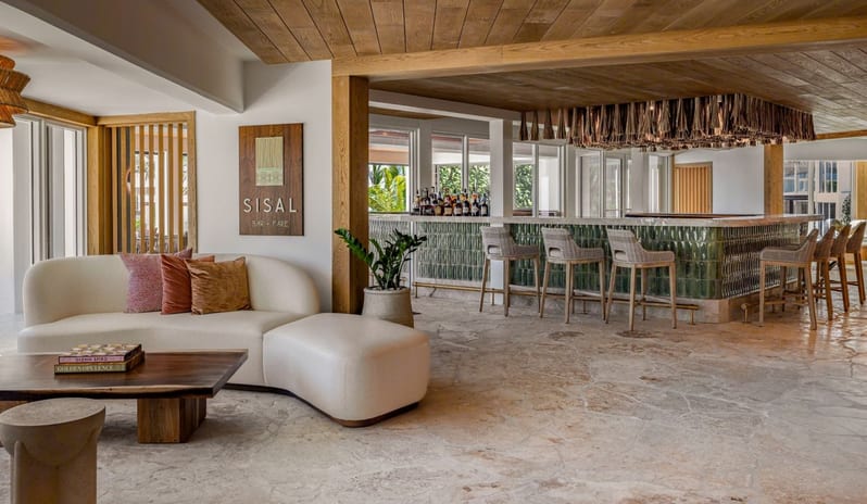 Sisal Bar lounge area with a curved white sofa and green tile bar with high stools at Salterra, A Luxury Collection Resort & Spa, South Caicos by Kenwood Travel