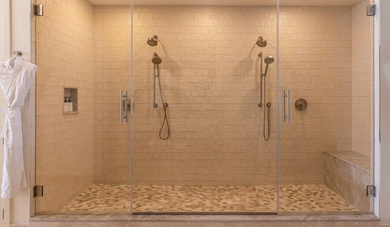 One Bedroom Ocean View King Suite Balcony bathroom shower featuring dual showerheads, pebble floor tile, and glass doors at Salterra, A Luxury Collection Resort & Spa, South Caicosby Kenwood Travel