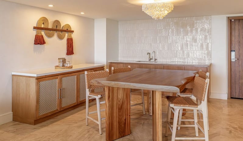 One Bedroom Ocean View King Suite Balcony dining room with a natural wood dining table, woven high chairs, and wet bar at Salterra, A Luxury Collection Resort & Spa, South Caicosby Kenwood Travel