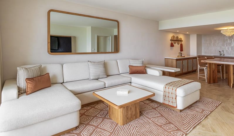 One Bedroom Ocean View King Suite Balcony living area with a large cream-colored sectional sofa, wooden coffee table, and open dining space at Salterra, A Luxury Collection Resort & Spa, South Caicosby Kenwood Travel